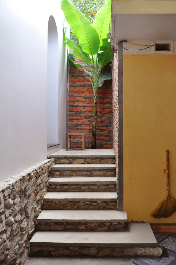 Description: Lối đi giữa căn nhà cũ và mới được thiết kế với mảng tường gạch mộc tạo cảm giác hòa quyện giữa 2 không gian 
